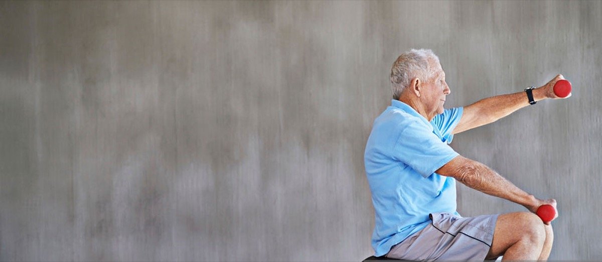 An older adult performing a seated strengthening exercise with light dumbbells