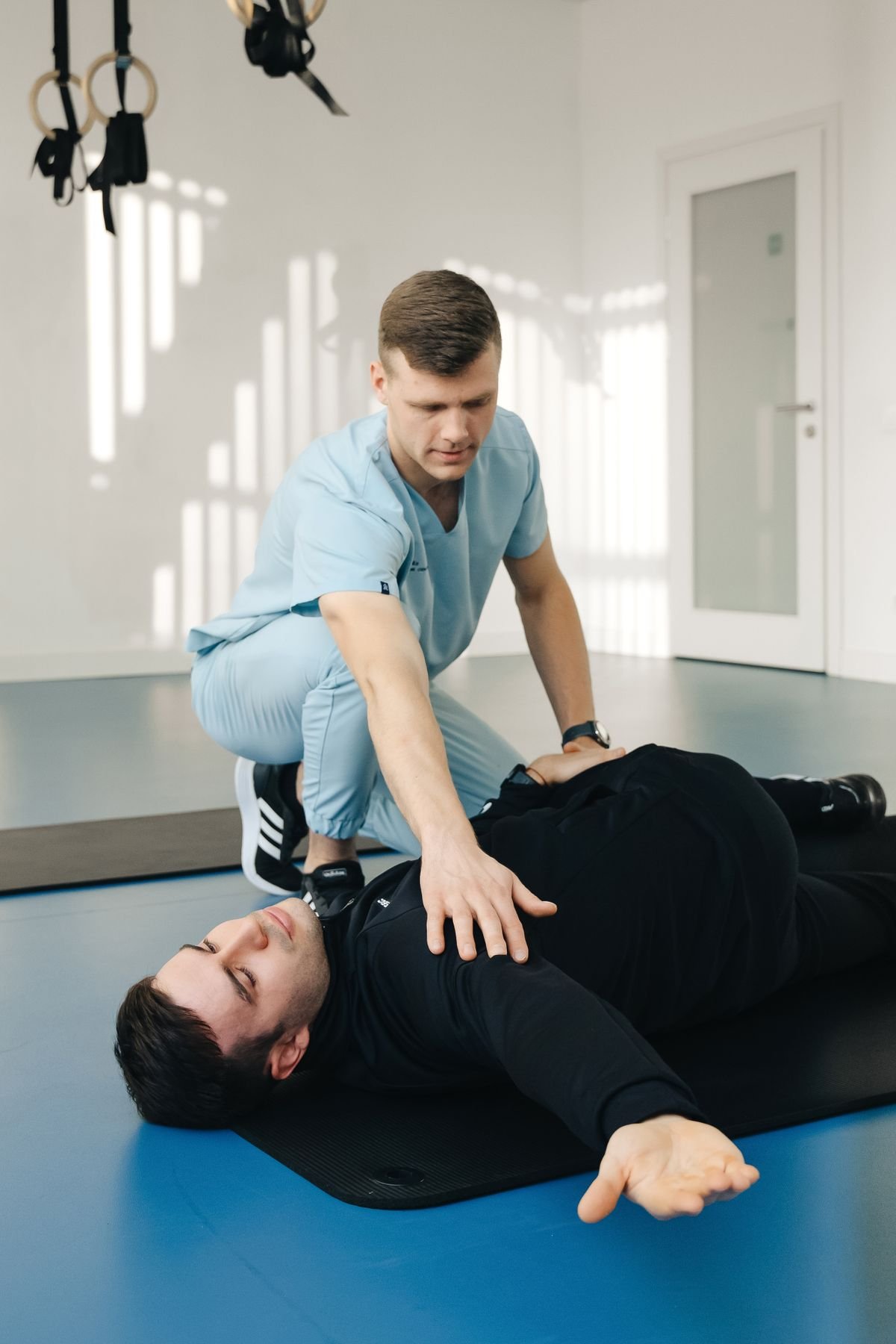 A physiotherapist guiding a patient through floor-based movement retraining